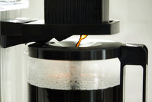 Coffee being poured from a coffee machine into a filter.