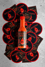 Orange bottle of Wicked Smart Lard surrounded by branded stickers on a gray concrete background